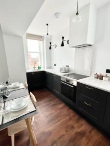 een keuken met zwarte kasten en een tafel met borden erop bij Redland Suites - Apartment 5 in Bristol