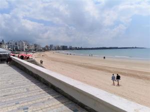 a group of people walking on the beach at L'Appart du Palais A 150m de la Grande Plage in Les Sables-dʼOlonne