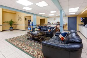 a living room with a leather couch and a table at Super 8 by Wyndham Newcomerstown in Newcomerstown