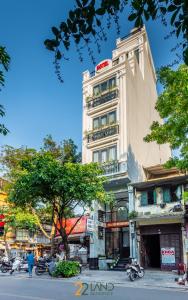 a tall white building with a tree in front of it at 22land Residence Hotel 71 Hang Bong Premium in Hanoi