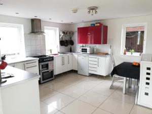 uma cozinha com electrodomésticos brancos e armários vermelhos em Cuilcagh House em Blacklion