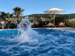 una fuente de agua en una piscina con sombrilla en Villa Ludilo mit 4 Apartments in Poljica - Marina bei Trogir Split, en Poljica