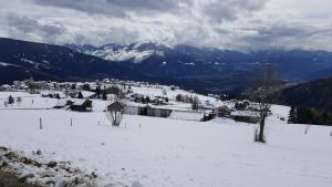 ein schneebedecktes Dorf mit Bergen im Hintergrund in der Unterkunft Pension Marianne in Meransen