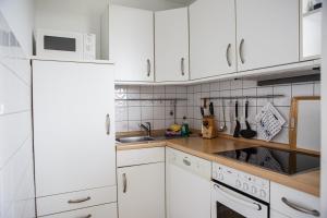 a white kitchen with white cabinets and a microwave at Langeneß Whg7 Seeperle in Wyk auf Föhr
