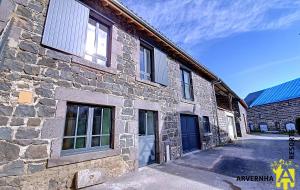 - un bâtiment en pierre avec des fenêtres sur le côté dans l'établissement Gîte des Pierres Bleues, à Saint-Genès-Champanelle