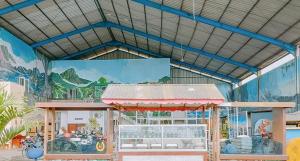 un bâtiment avec une fresque murale représentant un train sur le mur dans l'établissement RedDoorz @ Tongas Probolinggo, à Pesisir
