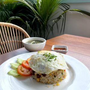 a white plate with a sandwich and vegetables on a table at Lavanya Boutique Hotel in Phnom Penh