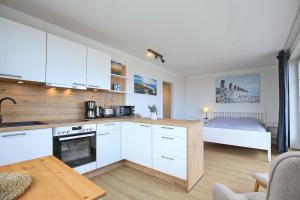 a kitchen with white cabinets and a bed in a room at Dünenblick Wohnung 51 in Boltenhagen