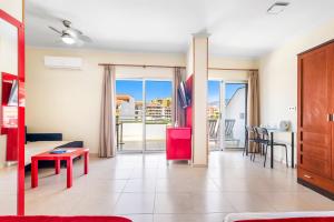 a living room with a red table and a balcony at Hotel Andrea´s in Los Cristianos