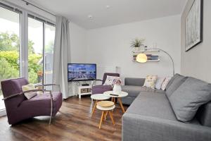 a living room with a couch and chairs and a tv at Residenz von Flotow Wohnung 04 in Heiligendamm