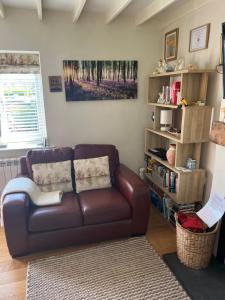 a living room with a brown couch and a book shelf at Lavender Cottage in Ripon