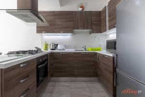 La cuisine est équipée d'armoires en bois et d'un réfrigérateur en acier inoxydable. dans l'établissement Sunny Penthouse wTerrace and Open Views, à San Pawl il-Baħar