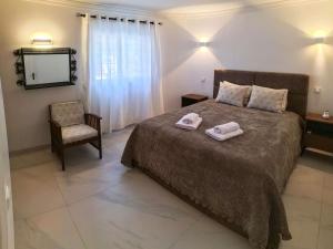 1 dormitorio con cama, silla y espejo en Casa beira mar Algarve, en Albufeira