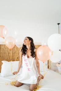 a woman sitting on a bed with balloons at Blue Harbour Boutique in Ayia Napa