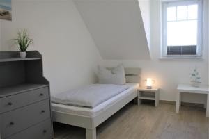 - une chambre blanche avec un lit et une fenêtre dans l'établissement Meerblick, à Timmendorfer Strand