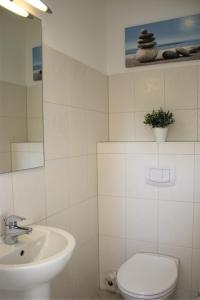 La salle de bains blanche est pourvue d'un lavabo et de toilettes. dans l'établissement Meerblick, à Timmendorfer Strand