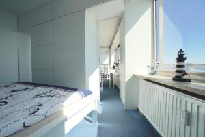um quarto branco com uma cama e uma janela em Ferienwohnung Schleiloge mit Panoramablick auf die Schlei em Schleswig