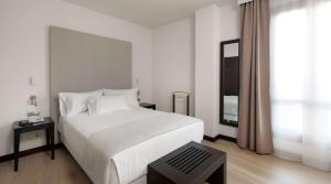 a white bedroom with a large bed and a window at Hotel Cartagena Puerto in Cartagena