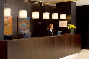a woman standing at a reception desk in a lobby at NH Valladolid Bálago in Valladolid