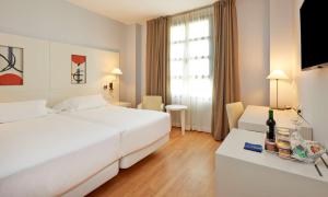 a hotel room with two beds and a television at NH Valencia Las Artes in Valencia