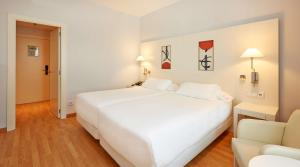 a hotel room with a bed, chair, and nightstand at NH Valencia Las Artes in Valencia