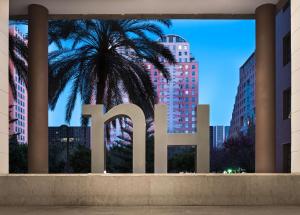a large sign with a palm tree in a city at NH Valencia Las Artes in Valencia