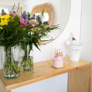 a shelf with vases of flowers and a cake at Blue Harbour Boutique in Ayia Napa