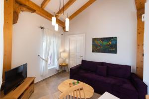 a living room with a purple couch and a tv at Avali Design Suites by Imagine Lefkada in Lefkada Town