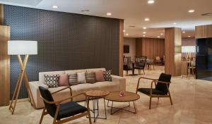 sala de estar con sofá, mesas y sillas en NH Ciudad de Valencia, en Valencia