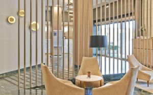 a lobby with chairs and a table with a lamp at NH Ciudad de Zaragoza in Zaragoza
