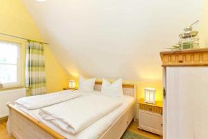 a bedroom with a large bed with white sheets at Ferienhaus Reethaus Koserow in Ostseebad Koserow