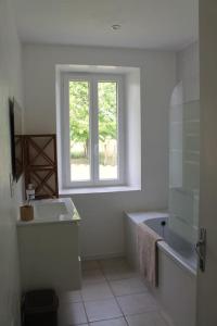 een badkamer met een bad, een wastafel en een raam bij Maison de campagne proche de Monpazier 