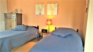 een slaapkamer met 2 bedden en een tafel met een lamp bij B&B Grenspaal 286 in Hillensberg