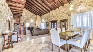 uma sala de jantar com uma parede de pedra e uma mesa e cadeiras em Zante Poolside Paradise - La Vite Stone Villa em Kalipádhon