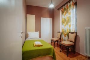 a small bedroom with a green bed and two chairs at Kalavrita downtown 3 bedroom house for 6 pers in Kalavrita