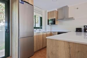 a kitchen with a white refrigerator and wooden cabinets at Precioso apartamento en Begur al lado de la playa Racó de Pals in Begur