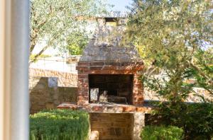 an outdoor brick oven in a yard with bushes at Villa Rustika in Dobrinj