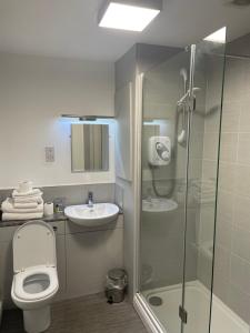 een badkamer met een douche, een toilet en een wastafel bij Littleover Lodge Hotel in Derby