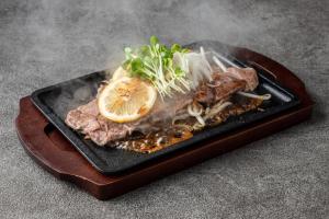 a black plate of food with meat and a lemon at Hotel LOVE JEWEL in Kitakyushu