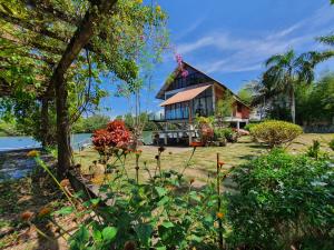 ein Haus auf dem Wasser mit Blumen davor in der Unterkunft Homestay ALA Riverview Lodge Kota Bharu in Kota Bharu
