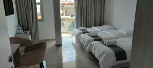 a hotel room with three beds and a window at La Veranda Hotel in Larnaca