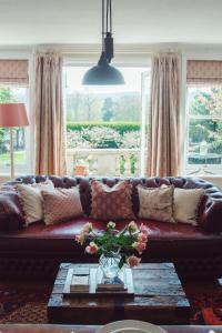 a living room with a brown leather couch with pillows at Traditional 18th Century Farmhouse in Streatley in Streatley