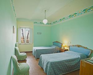 sypialnia z 2 łóżkami, krzesłem i oknem w obiekcie Villa La Fontana w mieście Castiglione del Lago +37 zdjęć