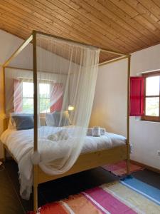 a bedroom with a canopy bed with a mosquito net at Casa Pedralva in Vila do Bispo