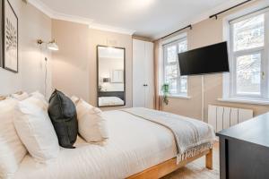 a bedroom with a bed with white pillows and a mirror at Be London - Covent Garden Residences in London