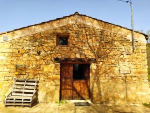 an old stone building with a wooden door and a ladder at Las Casitas del Salado - La Casita roja in Santamera