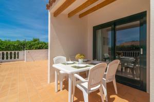 Una mesa blanca y sillas en un patio. en Villa Marina -Cala EnPorter-, en Cala'n Porter