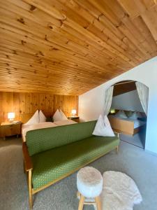a green couch in a room with a wooden ceiling at Ferienwohnung 4 in Taxenbach