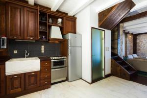 a kitchen with wooden cabinets and a white refrigerator at Volakas Beachfront Suites in Rethymno Town