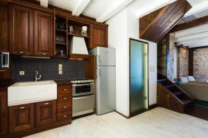 a kitchen with wooden cabinets and a white refrigerator at Volakas Beachfront Suites in Rethymno